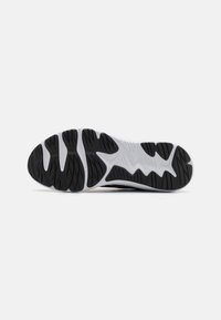 Shoe sole with a black rubber outer layer featuring a textured pattern. White midsole with wavy accents and distinct grooves for traction.