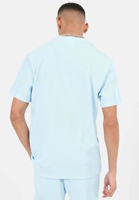 Heledsinine ribidega T-särk lühikeste varrukatega, ümar kaelus ja mugav lõige. Sile tekstuur ja peened vertikaalsed triibud.