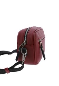 Bolso bandolera de imitación cuero rojo con herrajes plateados, forma rectangular, doble cremallera y correa ajustable negra. Superficie texturizada, diseño minimalista.