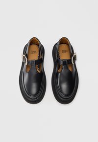 Zwarte leren schoenen met een T-bar ontwerp, verstelbare gesp en een stevige rubberen zool met zichtbare stiksels. Binnenvoering van bruin leer.