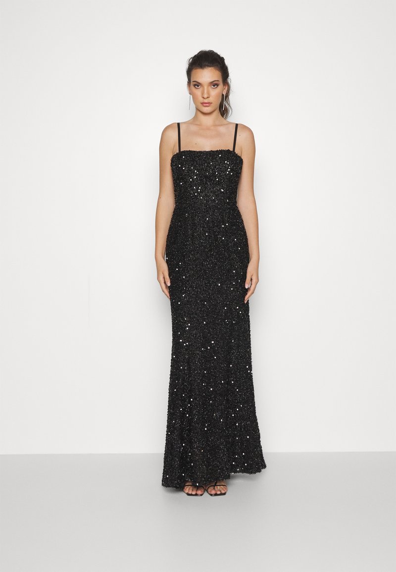 Abito da sera nero con paillettes, dotato di un corsetto aderente, scollatura dritta e spalline sottili, che scende fino a una gonna lunga fino al pavimento.