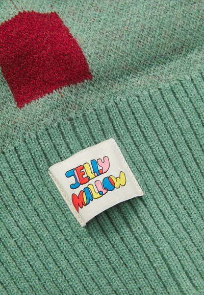 Grüner Strickstoff mit einem roten Quadratmuster und einem weißen Etikett, auf dem der bunte Text "Jelly Mallow" aufgenäht ist.