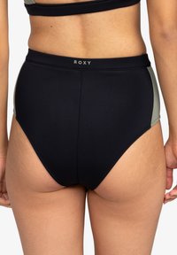 Hochgeschnittene Bikinihosen in Schwarz mit bisque-farbenen seitlichen Einsätzen. Hergestellt aus glattem, dehnbarem Material mit einem nahtlosen Bund.