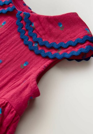 Różowa tkanina z niebieską falbanką, z kwiatowym wzorem drobnych niebieskich kwiatów i zielonych liści na powierzchni.