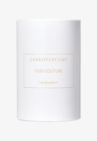 Vit cylindrisk doftförpackning med guldtext. Etiketten lyder "ZARKOPERFUME OUD-COUTURE eau de parfum." Slät yta, minimalistisk design.