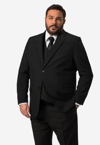 Giacca nera con una texture liscia, chiusura a un bottone, due tasche frontali, abbinata a un gilet e una cravatta neri, con polsini di camicia bianchi.