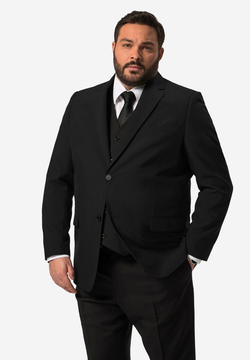 Giacca nera con una texture liscia, chiusura a un bottone, due tasche frontali, abbinata a un gilet e una cravatta neri, con polsini di camicia bianchi.