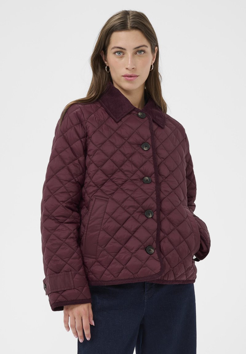 Gestepptes kastanienbraunes Jackett mit einem Cordkragen, fünf schwarzen Knöpfen und seitlichen Taschen, das eine weiche Textur und einen lässigen Schnitt aufweist.