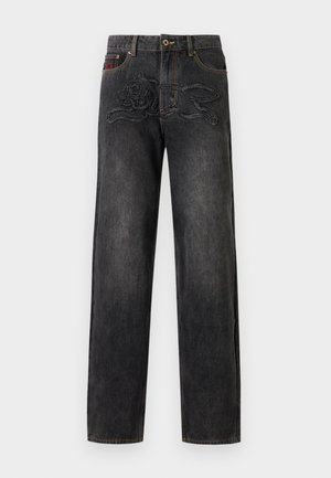 Jeans en denim noir avec un motif de lapin cousu sur le devant et un détail brodé rouge près de la poche supérieure gauche.