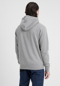 Grå hoodie med tjock huva, ribbade muddar och fåll; gjord av mjuk bomullsblandning, med en enkel enfärgad design.