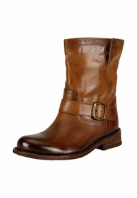 Bottines en cuir marron avec un embout rond, une large sangle dotée d'une boucle en laiton et un petit talon empilé. Texture lisse et design décontracté.