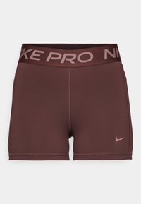 Bordeaux idrettsshorts med bred, mørk midje som har teksten "NIKE PRO". Glatt tekstur med en liten rosa Nike-logo på siden.