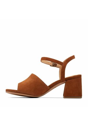 Bruine suède sandalen met blokhakken, voorzien van een brede teenband en een verstelbare enkelband. De hak is ongeveer 5 cm hoog.