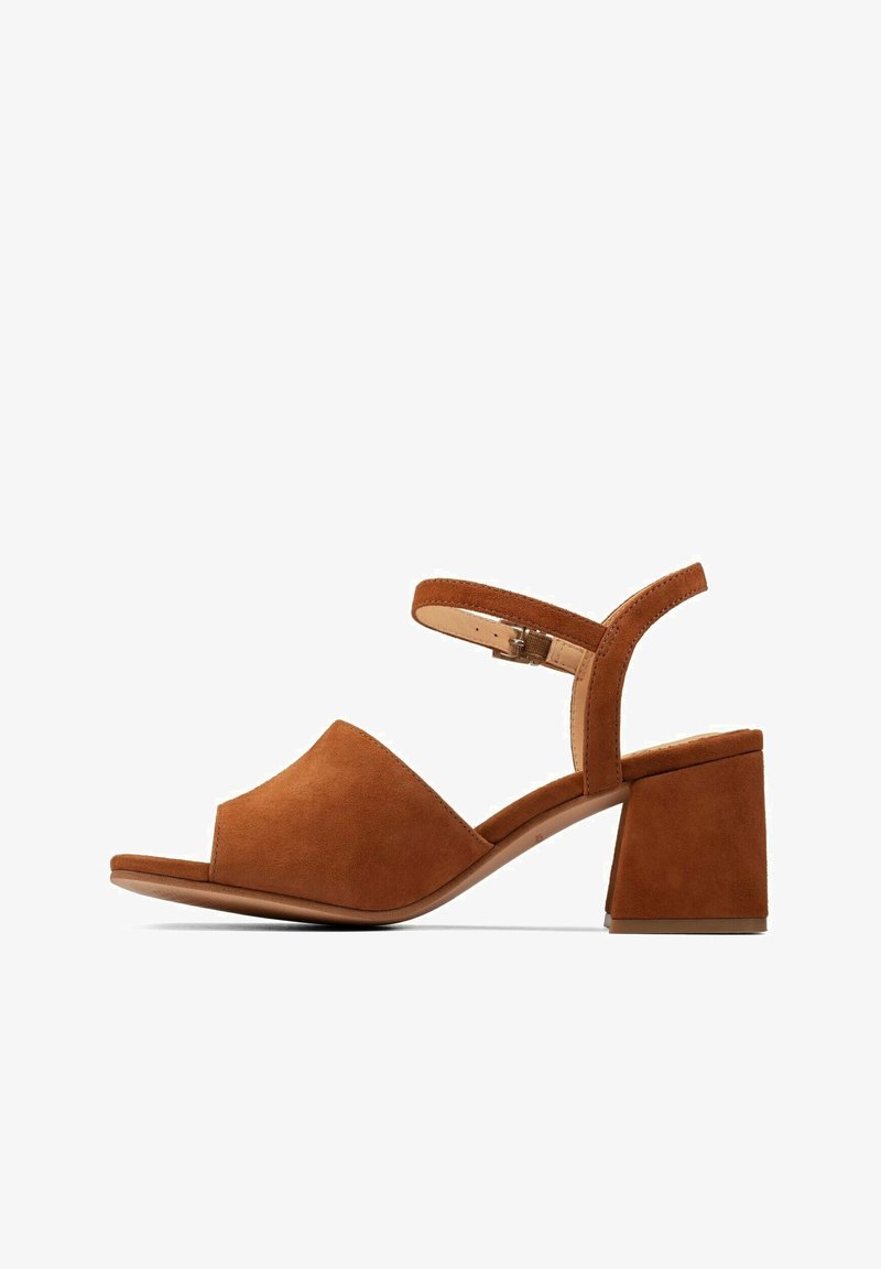 Sandales à talon bloc en daim marron avec une large sangle à l'avant et une bride réglable à la cheville. Le talon mesure environ 5 cm de hauteur.