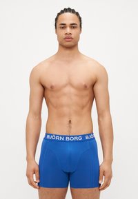 Blaue Boxershorts mit einem weißen "BJÖRN BORG" Logo-Bund, aus dehnbarem Stoff, mit einer taillierten Passform und glatter Textur.