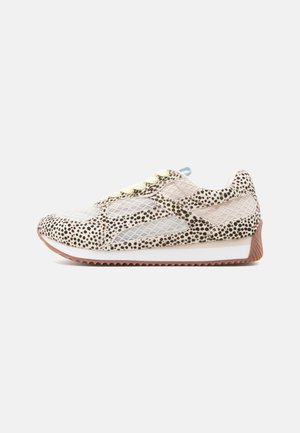 Sneaker met een bovenwerk van mesh met een beige en zwart gespikkeld patroon, gele veters en een getextureerde bruine rubberen zool.