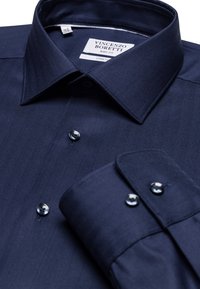 Navyblauwe overhemdd met een visgraatpatroon, puntkraag en zilveren knopen. Etiket leest "Vincenzo Boretti, Body Fit, Stretch."