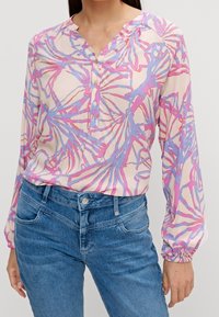 Blouse colorée en rose clair avec des motifs abstraits bleus et violets, dotée d'un col en V, d'une patte de boutonnage et de manches longues froncées.