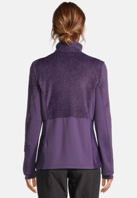 Pullover in pile viola con collo alto, spalle testurizzate e maniche lunghe. Pannello anteriore e posteriore liscio, cuciture dettagliate e vestibilità ampia.