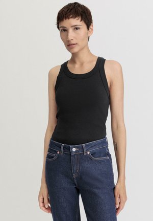 Zwarte geribbelde tanktop met een ronde hals, gecombineerd met hoge blauwe denim jeans met oranje stikseldetails en een sluiting met een knoop aan de voorkant.
