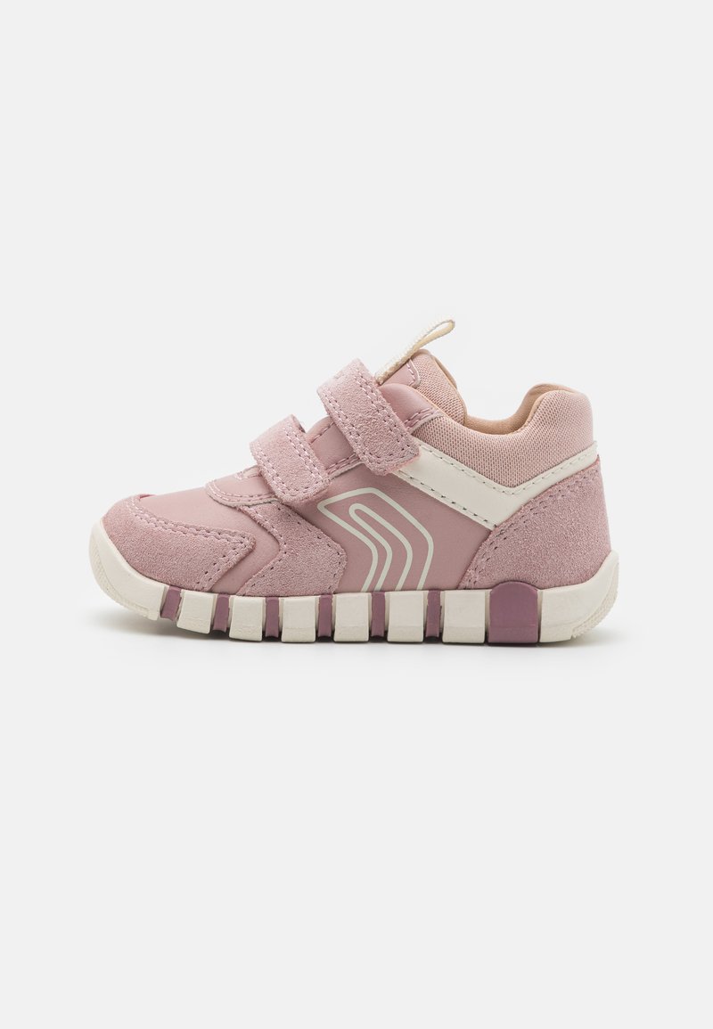 Zapatilla deportiva rosa con materiales de ante y malla, que cuenta con dos correas de velcro, una franja blanca de acento y una suela de goma texturizada.
