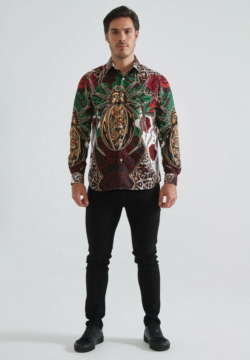 Chemise à boutons multicolore avec un graphisme d'araignée, des motifs floraux et léopards. Fabriquée en tissu doux, avec des manches longues et un col.