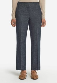 Mörkblå skräddarsydda byxor i stickad tyg, med en smal silhuett, veck fram, och elastisk midja, kombinerat med bruna sandaler.