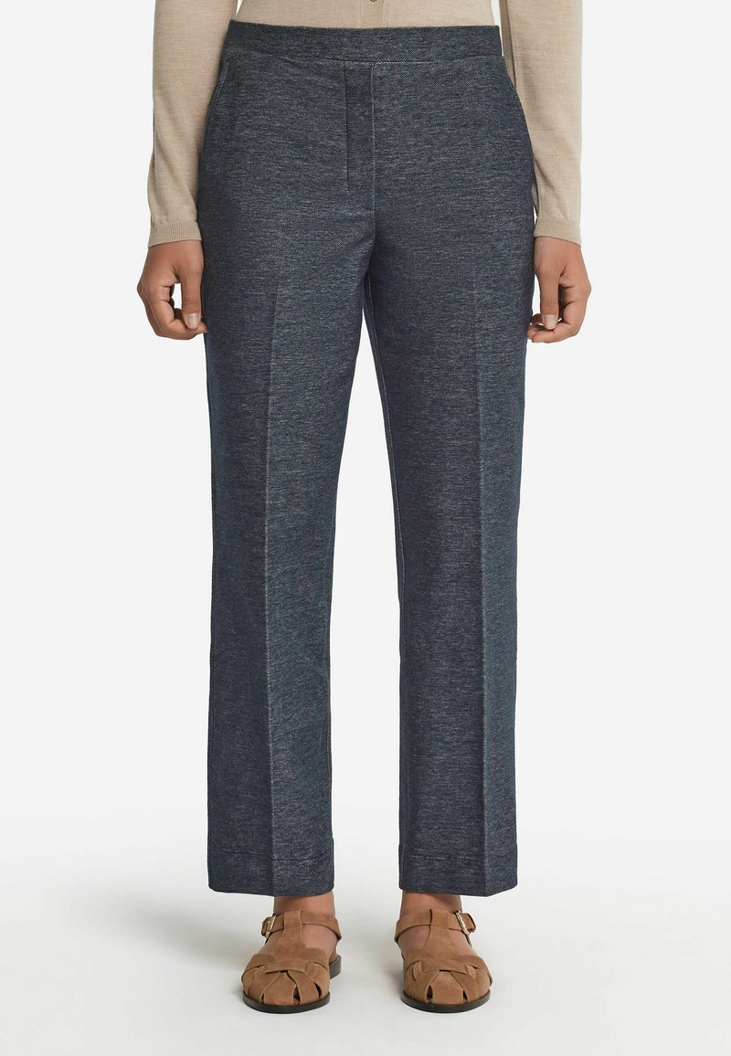 Mörkblå skräddarsydda byxor i stickad tyg, med en smal silhuett, veck fram, och elastisk midja, kombinerat med bruna sandaler.