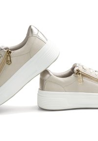 Sneaker beige con tomaia in pelle texturizzata, dettagli metallici, una cerniera laterale e una suola in gomma bianca spessa con un motivo rigato.