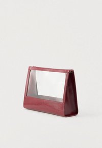 Κόκκινη δερμάτινη τσάντα με διαφανές μπροστινό πάνελ και δομημένο σχέδιο. Ομαλή υφή, κλείσιμο με φερμουάρ, ορθογώνιο σχήμα και ματ φινίρισμα.