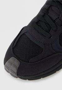 Shoe sportiv de o culoare bleumarin închis, având un superior din plasă și suprapuneri din suede. Include un vârf texturat și detalii din cauciuc negru la talpă.