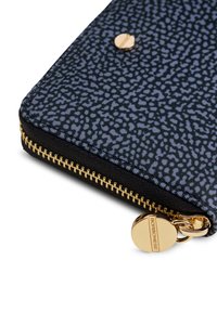 Portefeuille noir zippé avec un imprimé bleu texturé, des fermetures éclair dorées, et un accent de logo circulaire. Forme compacte et rectangulaire.