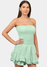 Mintgroene, strapless jurk met een gerimpelde corsage en een uitlopende, gerimpelde zoom. Gemaakt van gestructureerde, lichte stoffen.