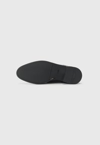 Suela de zapato de cuero negro con una textura suave. Presenta una puntera redondeada y un sutil detalle en relieve, con un tacón plano y un agarre duradero.