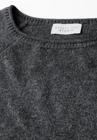 Dunkelgrauer, gestrickter Rundhalsausschnitt-Pullover mit einem weißen Etikett, auf dem "Street One Studio" steht, das im Kragen eingenäht ist.
