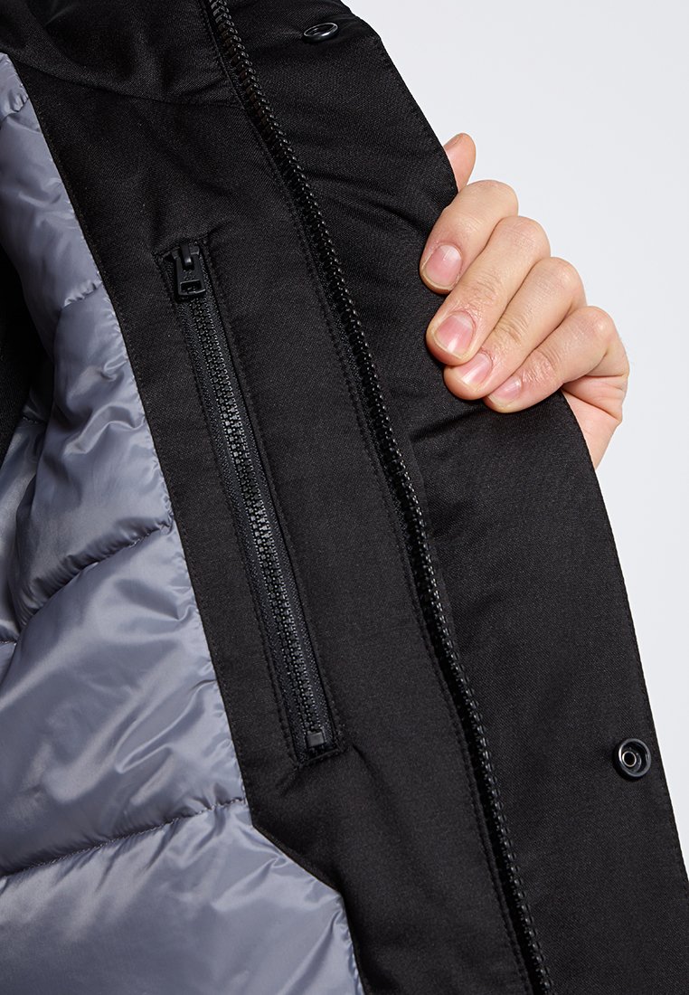 Tissu extérieur noir avec une doublure intérieure grise lisse et brillante. Comprend une poche zippable, des coutures visibles et des boutons-pression.