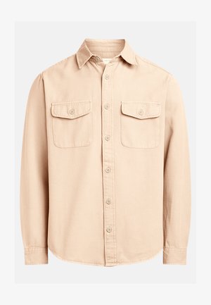 Chemise beige à col, à boutons, fabriquée dans un tissu texturé, avec une patte de boutonnage à l'avant et deux poches poitrine avec rabats à boutons.
