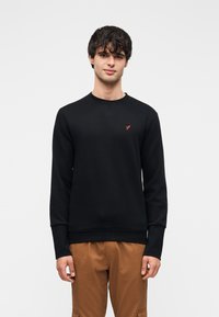 Μαύρο φούτερ κατασκευασμένο από βαμβάκι. Διαθέτει στρογγυλή λαιμόκοψη, μακριά μανίκια και ένα μικρό κόκκινο λογότυπο στο στήθος. Κλασική εφαρμογή.