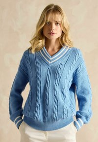 Pulover tricotat de culoare albastru deschis, cu decolteu în V, având modele cu cabluri și manșete în dungi. Textură moale și design cu croială lejeră.