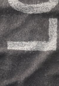 Sivi tkanina s kontrastnim bijelim geometrijskim oblicima, kružnim uzorkom i pravokutnim dijelom, prikazuje meku, teksturiranu površinu.