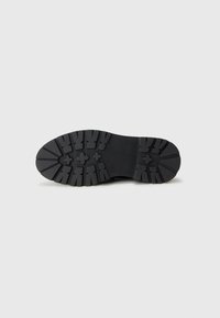 Black rubber sole with deep treads and a smooth upper surface, featuring a central crossing ridge and five-pointed star accents in the pattern.