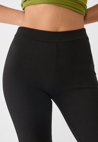Crne tajice s glatkim, rastezljivim materijalom, s visokim strukom i bezšavnom dizajnom za elegantan izgled.
