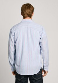 Light blue long-sleeve shirt with vertical red and white stripes, featuring a button-down collar and curved hem, made of cotton fabric.