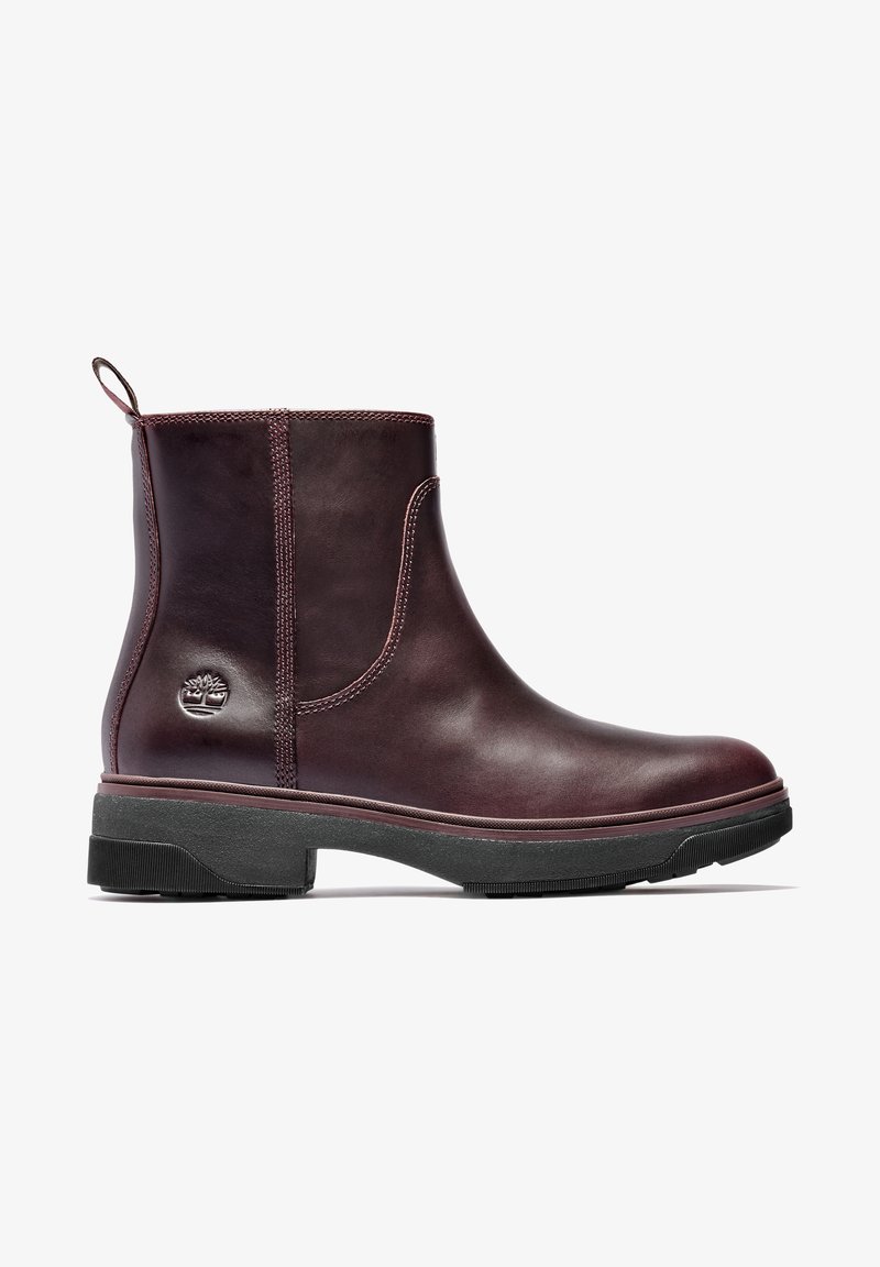 Bottine en cuir brun foncé avec languette de traction, semelle épaisse noire texturée, et logo arbre Timberland embossé sur le côté du talon.