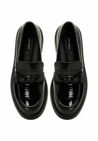 Black patent leather loafers with a rounded toe, raised stitching detail, and a textured sole for grip; branded insole visible.