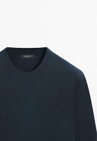 Maglione blu navy lavorato a maglia con scollo rotondo, polsini a coste e texture liscia. Etichetta con la scritta "Massimo Dutti." Senza motivi o dettagli visibili.