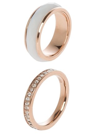 Deux bagues en or rose, l’une avec une incrustation en céramique blanche et l’autre avec une rangée de petits pierres précieuses transparentes autour de l’anneau.