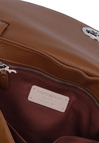 Borsa a tracolla in pelle marrone con superficie texturizzata, hardware in argento e interno bordeaux. Presenta un'etichetta del marchio e una chiusura con zip.
