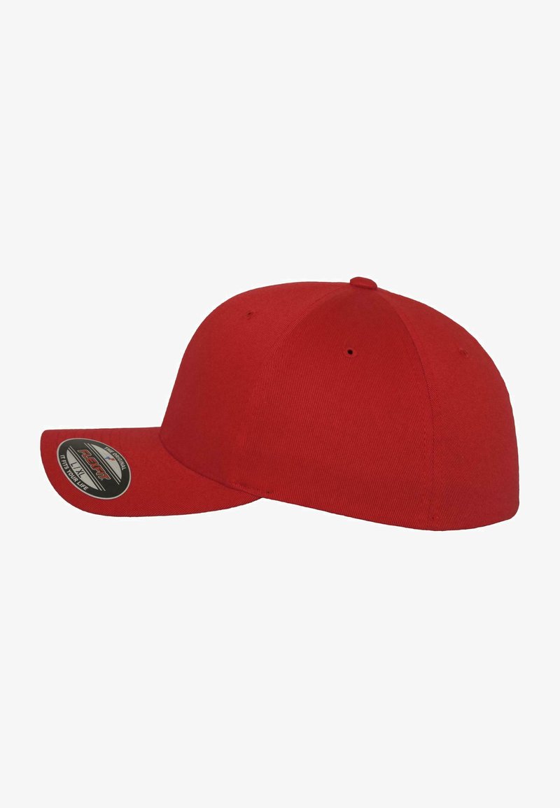 Piros baseball sapka ívelt karimával, strukturált koronával és textúrált anyagból. A bal oldalán egy kör alakú címke található.