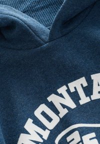 Felpa blu con cappuccio, tessuto strutturato; presenta una grande scritta bianca "MONTANA" sul petto e un design a badge rotondo.